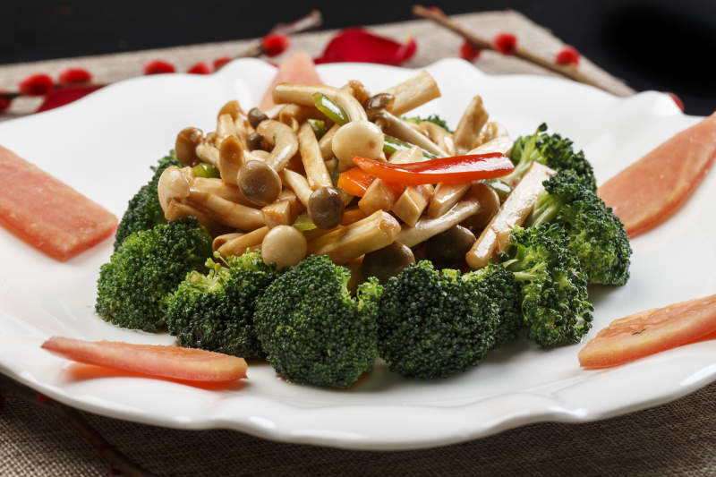 白色瓷盘装的杂菌炝炒西蓝花图片