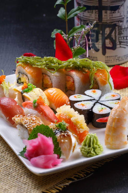 长方形白瓷盘装的豪华寿司拼盘摆放在草垫上图片