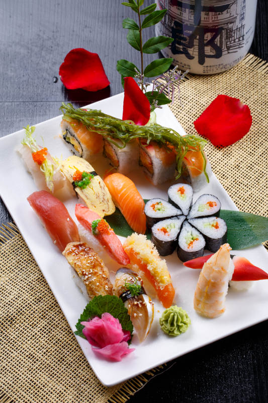 长方形白瓷盘装的豪华寿司拼盘摆放在草垫上图片