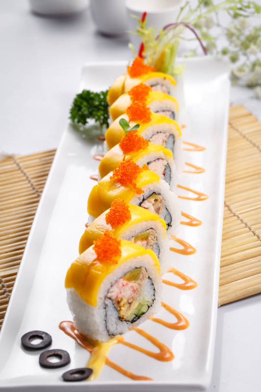 黄金甲蟹子寿司卷摆放在寿司帘上图片