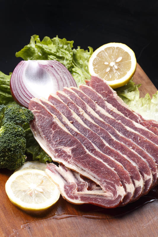 搭配柠檬洋葱生菜的牛肋排摆放在木质砧板上图片