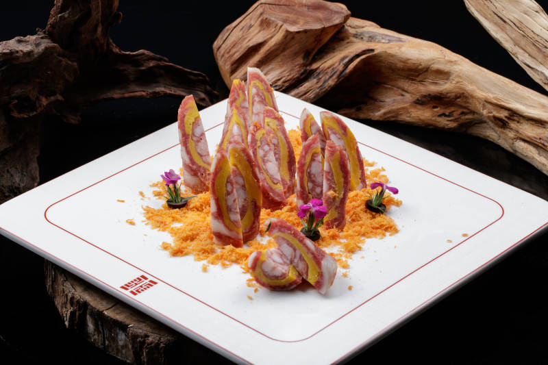 寿司帘上的扇形瓷盘装的自制川味腊肉香肠图片