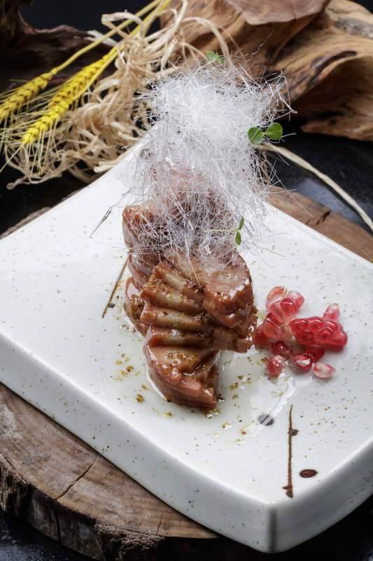 青瓷盘装的糖丝蜂蜜黄米藕摆放在樟木砧板上图片