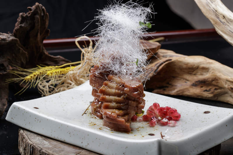 青瓷盘装的糖丝蜂蜜黄米藕摆放在樟木砧板上图片