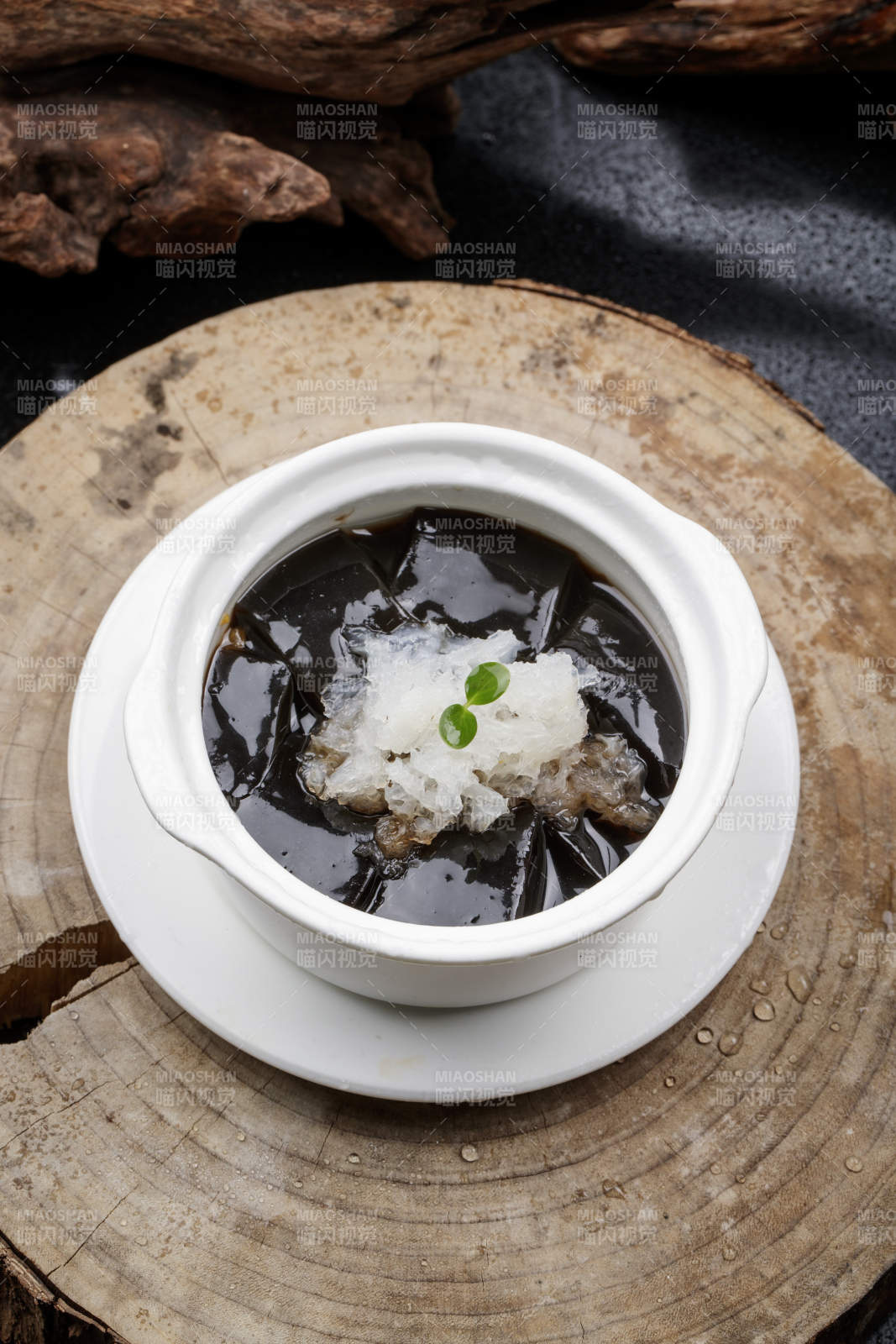 白色汤盅装的银耳龟苓膏摆放在樟木砧板上图片