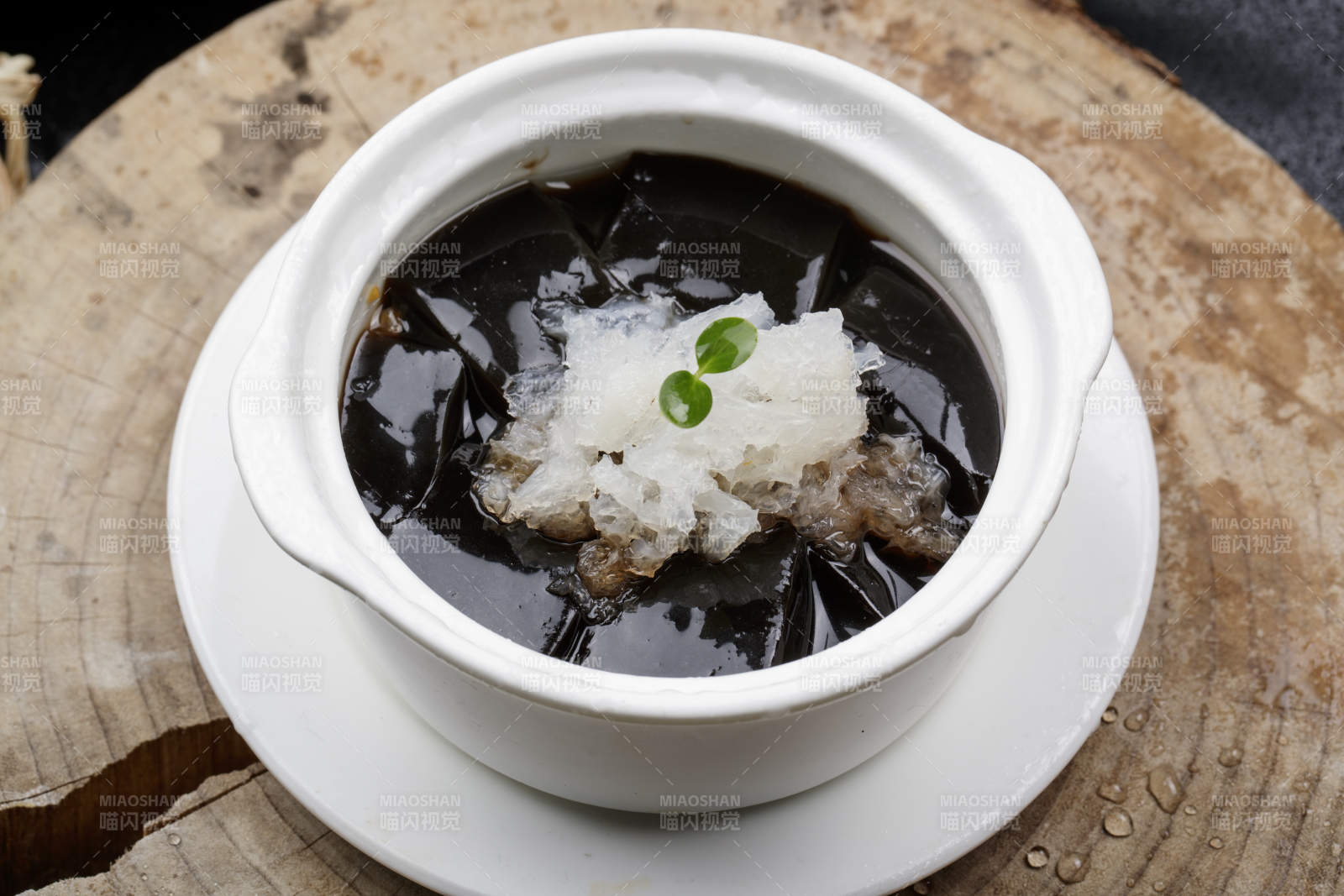 白色汤盅装的银耳龟苓膏摆放在樟木砧板上图片
