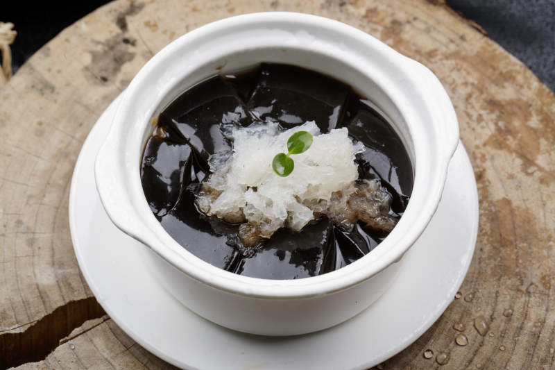 白色汤盅装的银耳龟苓膏摆放在樟木砧板上图片