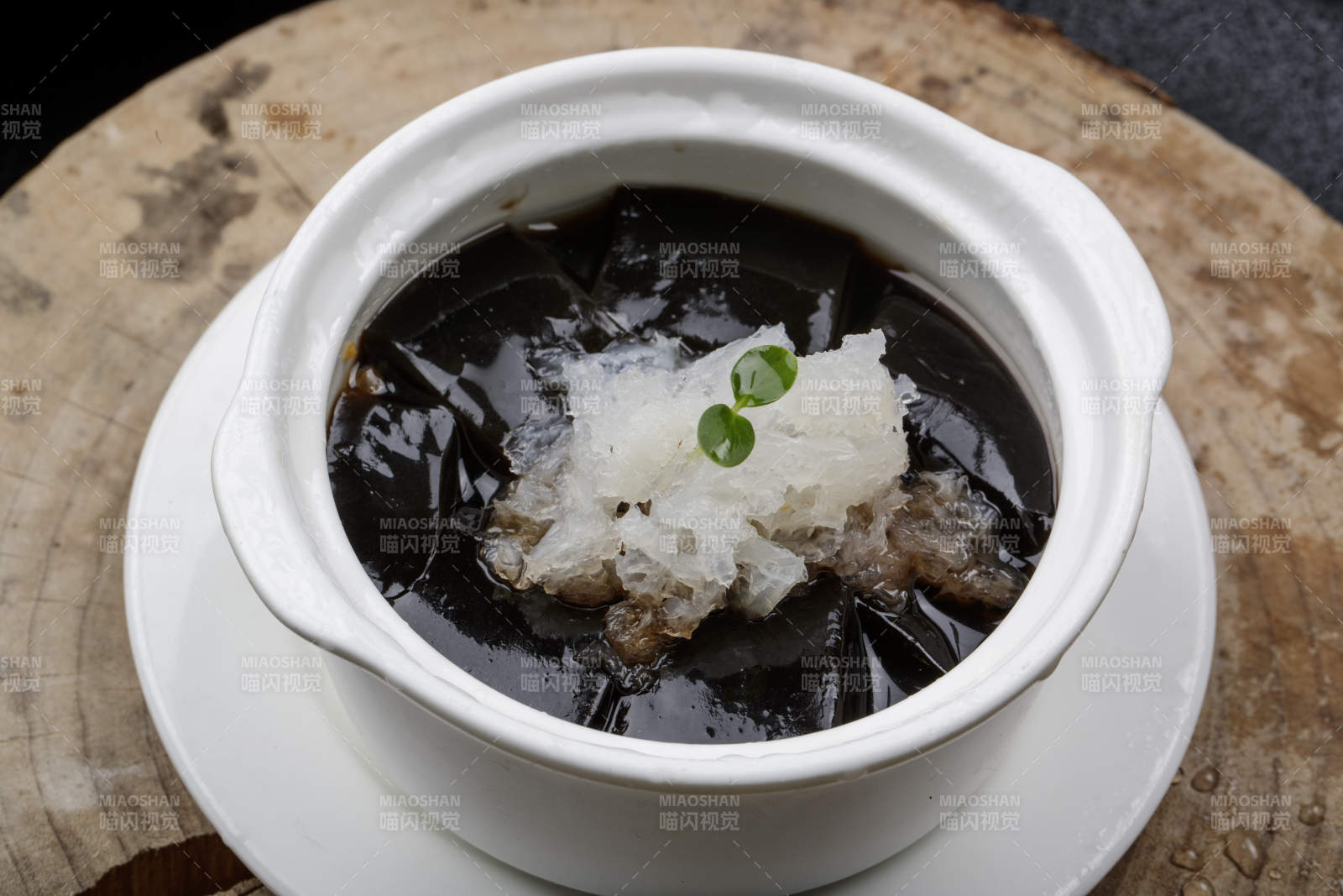 白色汤盅装的银耳龟苓膏摆放在樟木砧板上图片