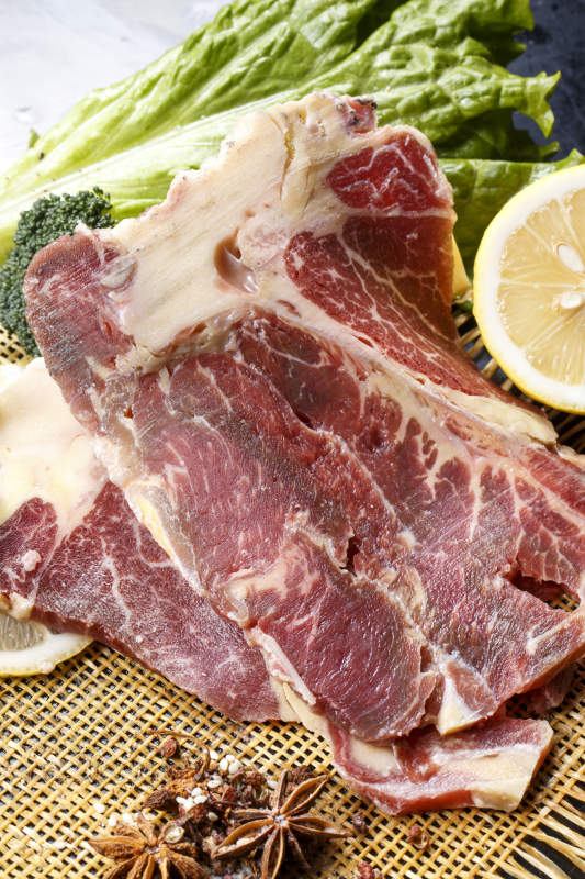 黑色背景草垫上的T骨牛排配柠檬图片