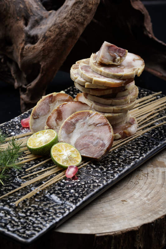 烟熏豆皮肘花卷摆放在樟木砧板上图片