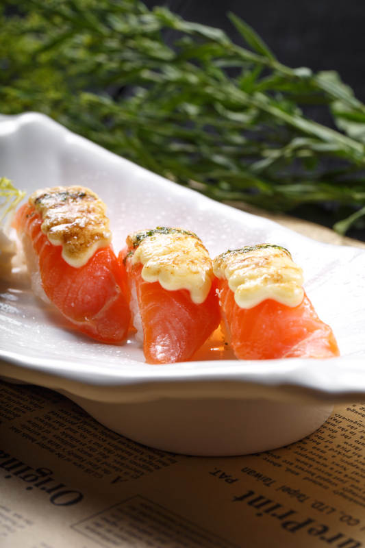 芝士焗三文鱼手握寿司摆放在英文包装纸上图片