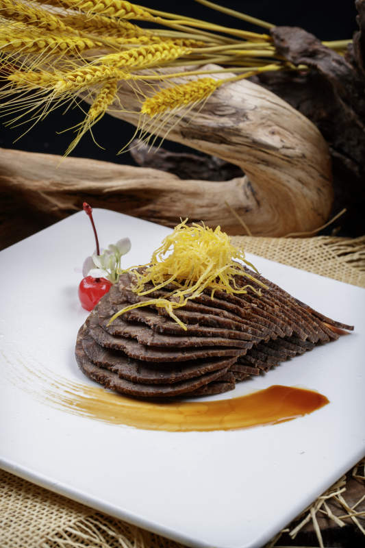 方形瓷盘装的五香酱牛肉摆放在麻布垫子上图片