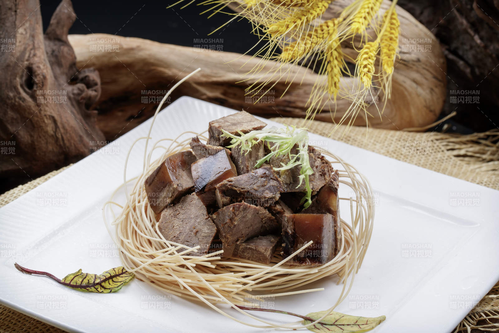 方形瓷盘装的老卤汤牛方粒摆放在麻布垫子上图片