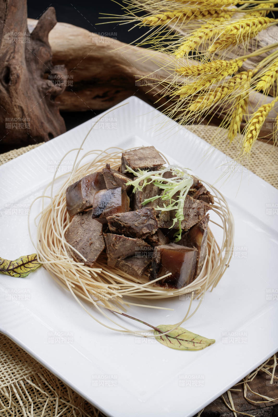 方形瓷盘装的老卤汤牛方粒摆放在麻布垫子上图片
