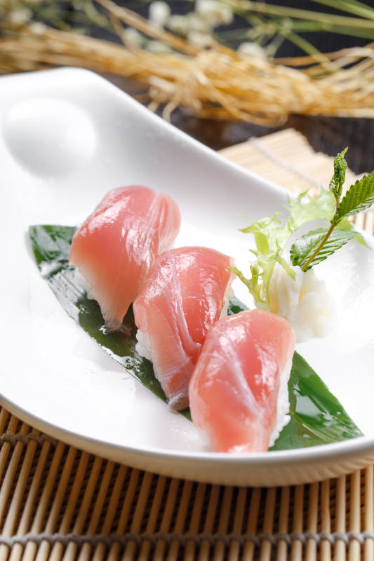 金枪鱼手握寿司摆放在寿司帘上图片