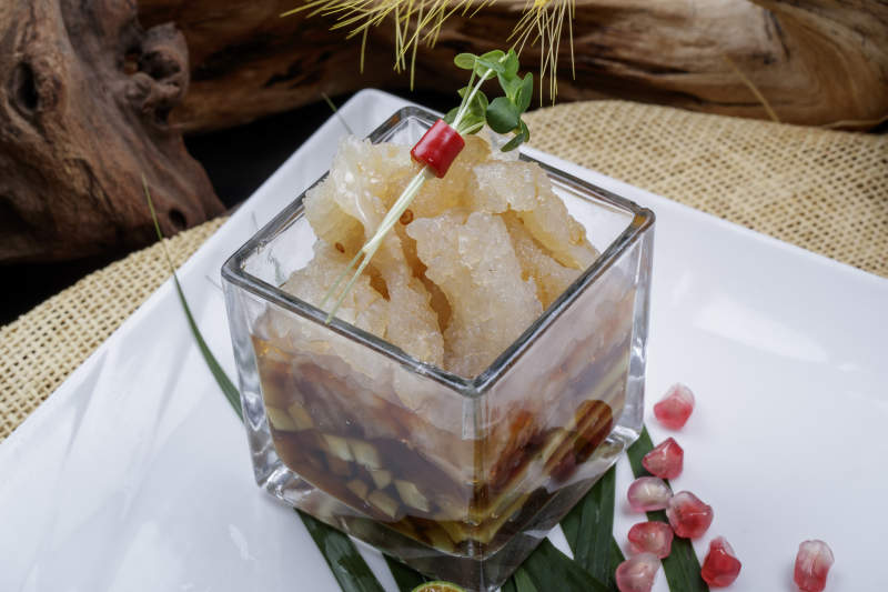 玻璃方盅装的老醋蛰头摆放在樟木砧板上图片