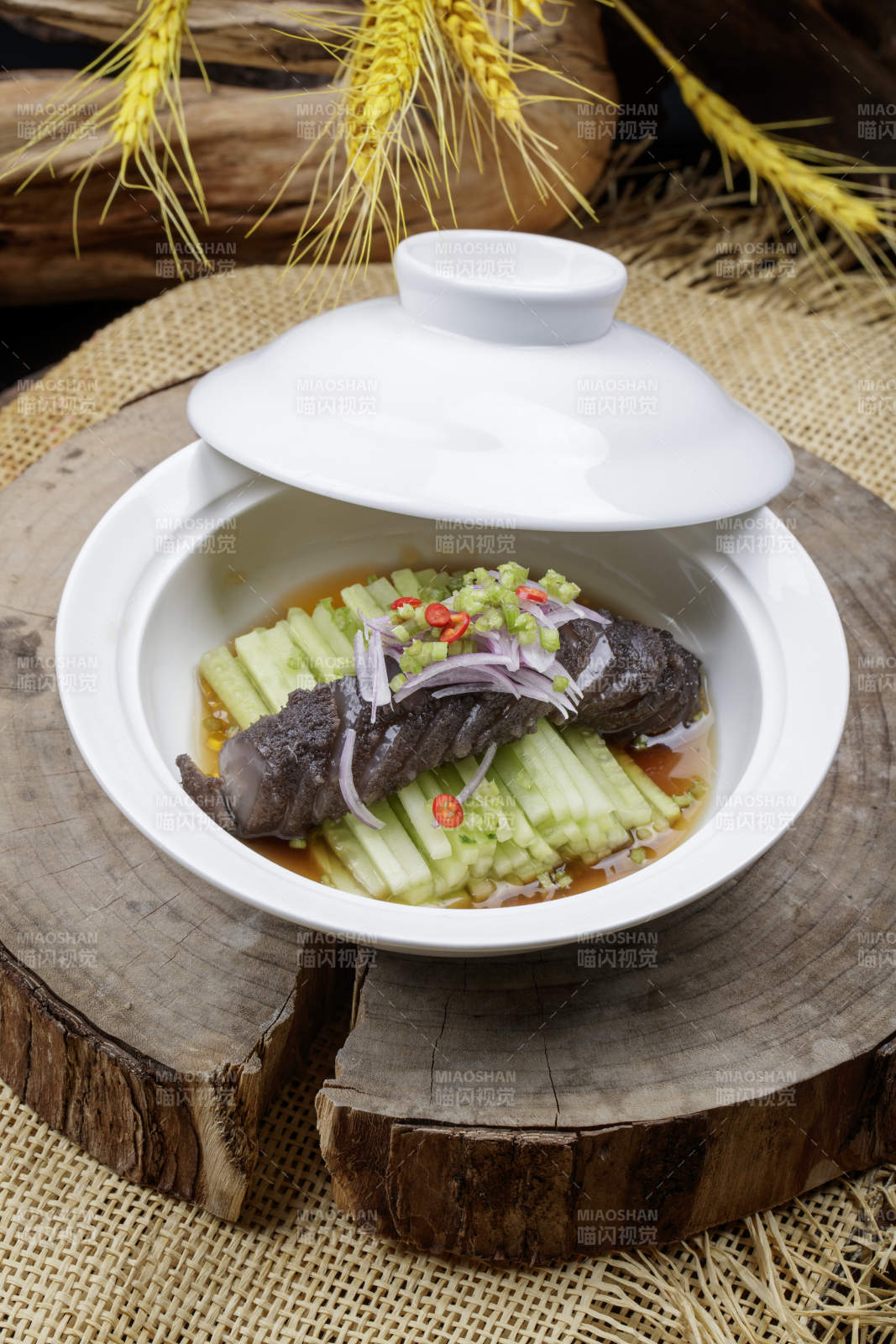 白色汤碗装的锅烧大海参摆放在樟木砧板上图片