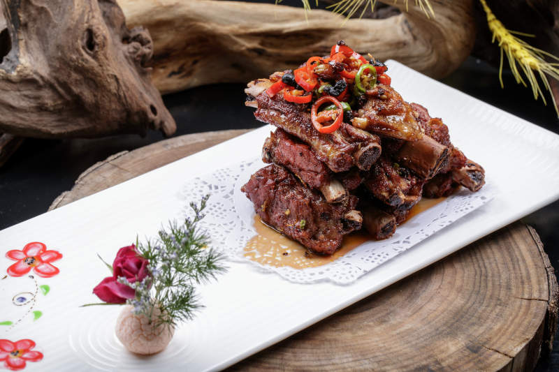 长方形瓷盘装的豆豉蒸排骨摆放在樟木砧板上图片