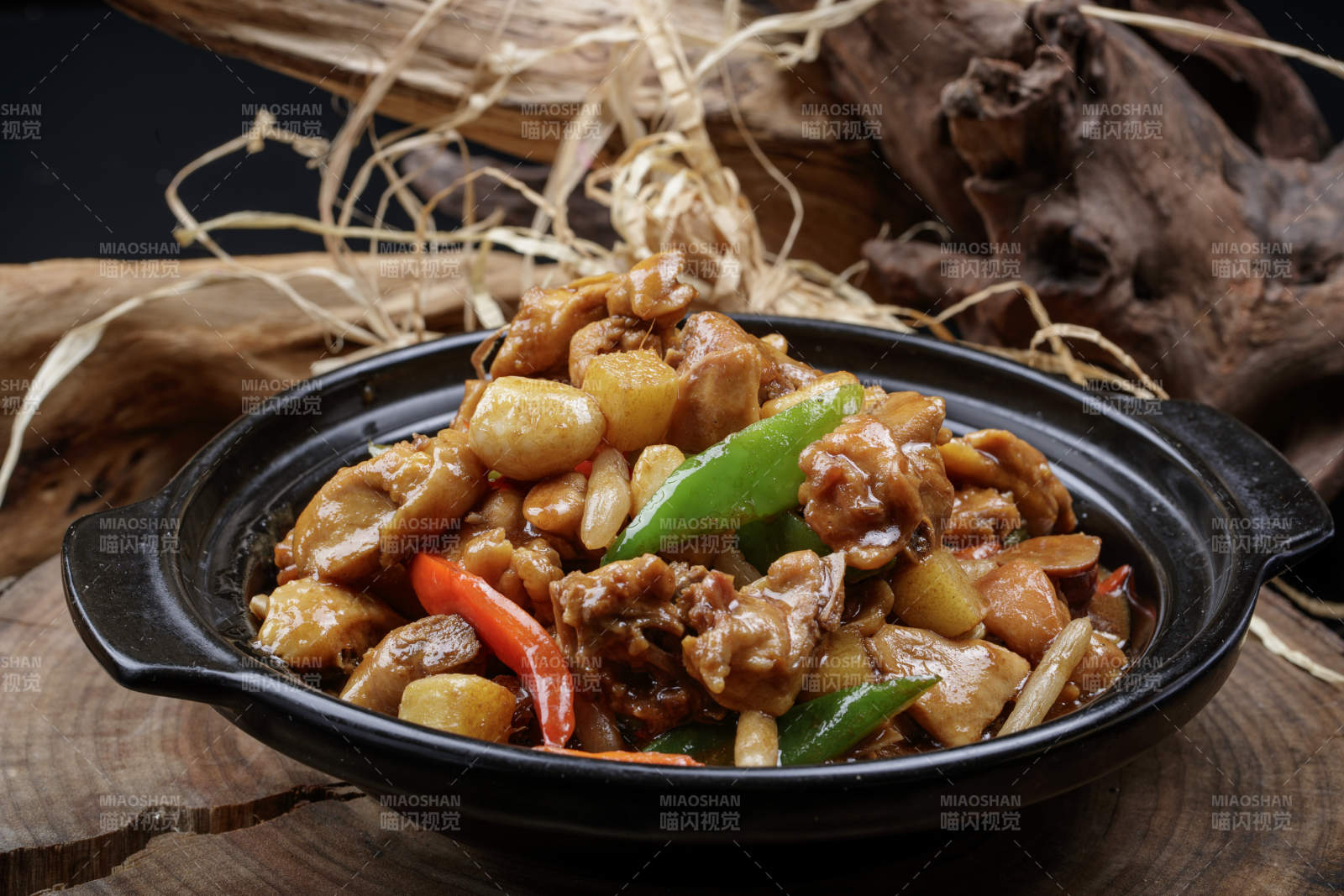 黑色砂锅装的砂锅蒜香鸡摆放在樟木砧板上图片