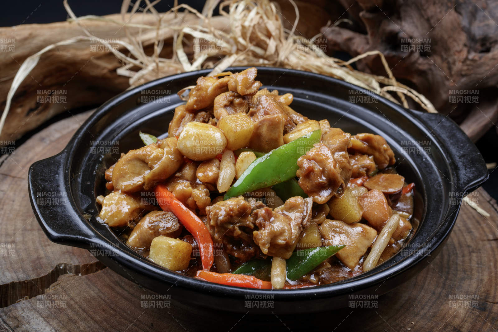 黑色砂锅装的砂锅蒜香鸡摆放在樟木砧板上图片