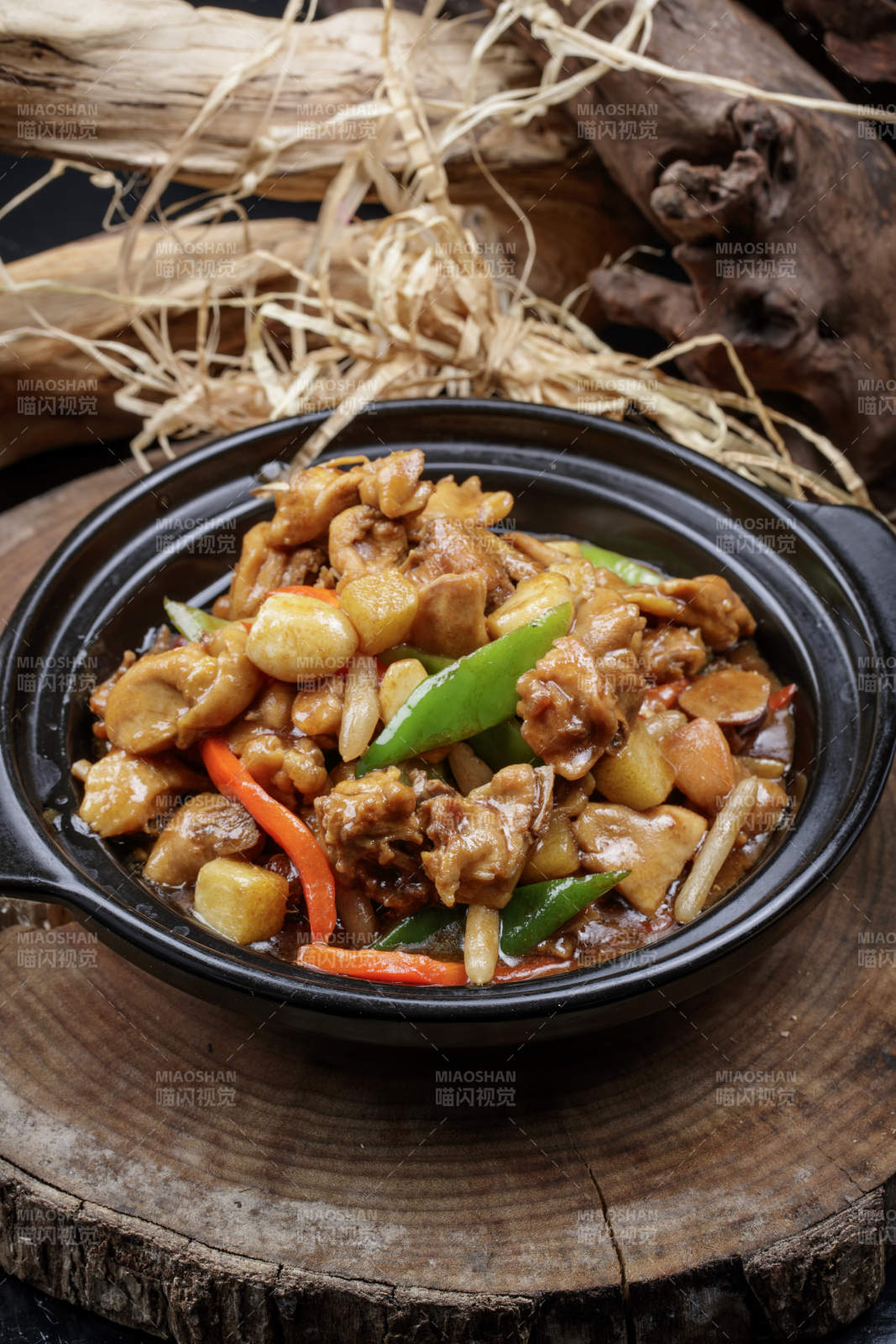 黑色砂锅装的砂锅蒜香鸡摆放在樟木砧板上图片