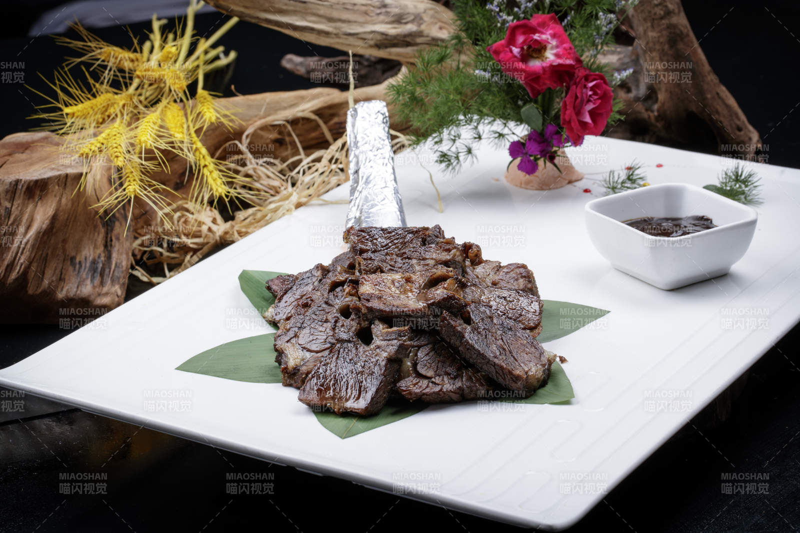 方形瓷盘装的炭烤牛肋排摆放在黑色背景上图片