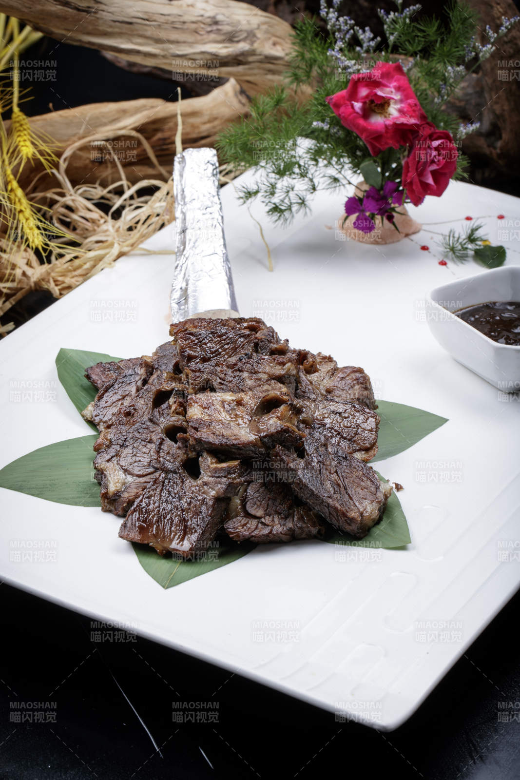 方形瓷盘装的炭烤牛肋排摆放在黑色背景上图片