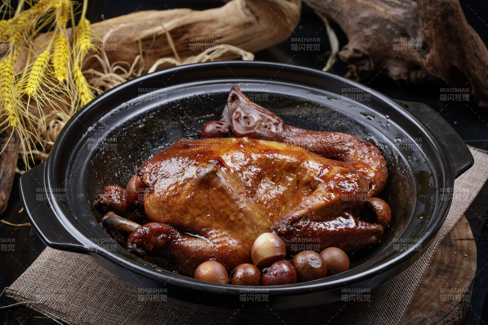 黑色砂锅装的生噘鸡煲摆放在幕布垫子上图片