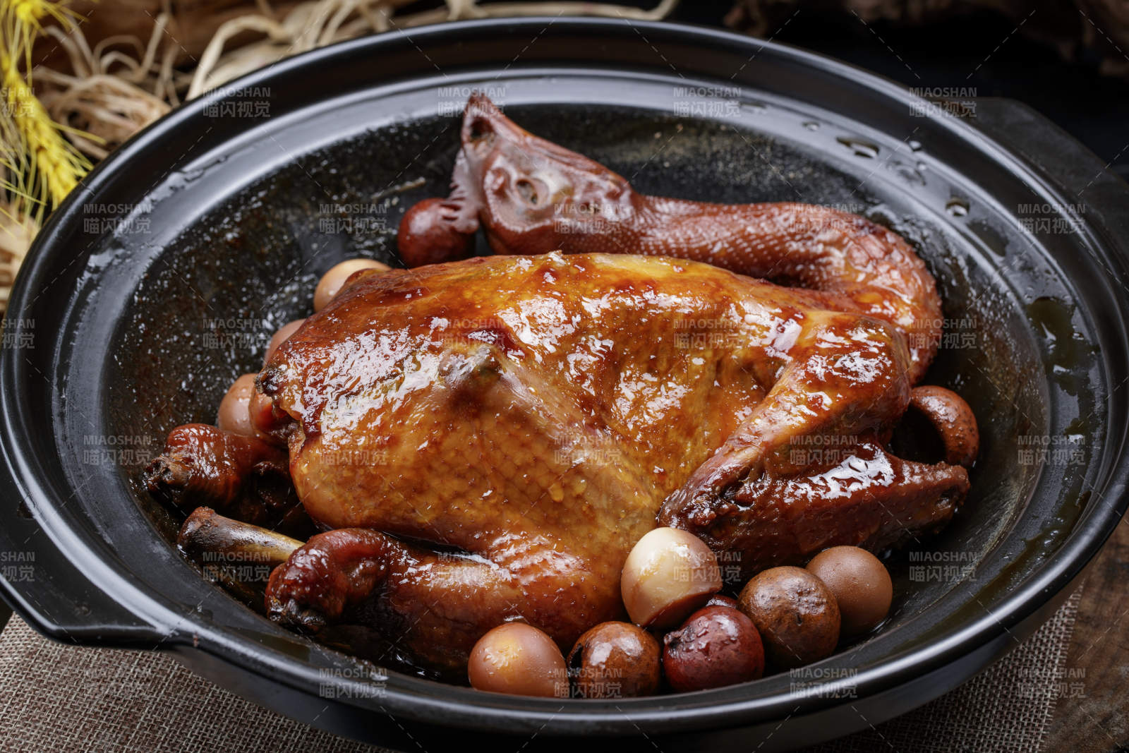 黑色砂锅装的生噘鸡煲摆放在幕布垫子上图片