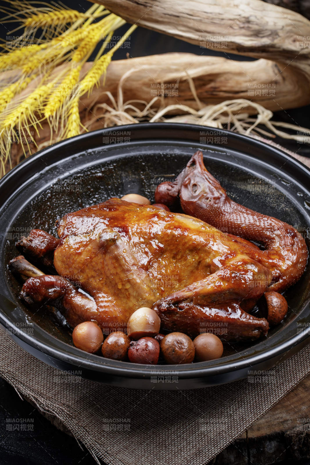 黑色砂锅装的生噘鸡煲摆放在幕布垫子上图片