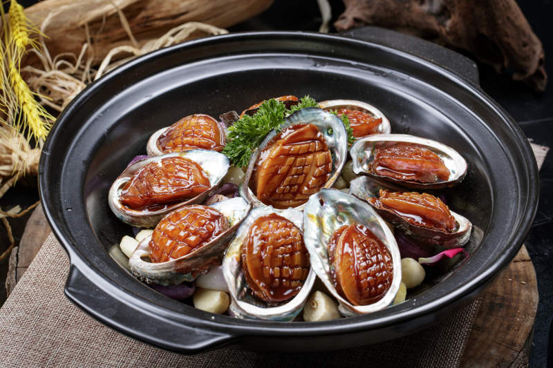 蒜焗砂锅鲜鲍鱼摆放在麻布垫子上图片