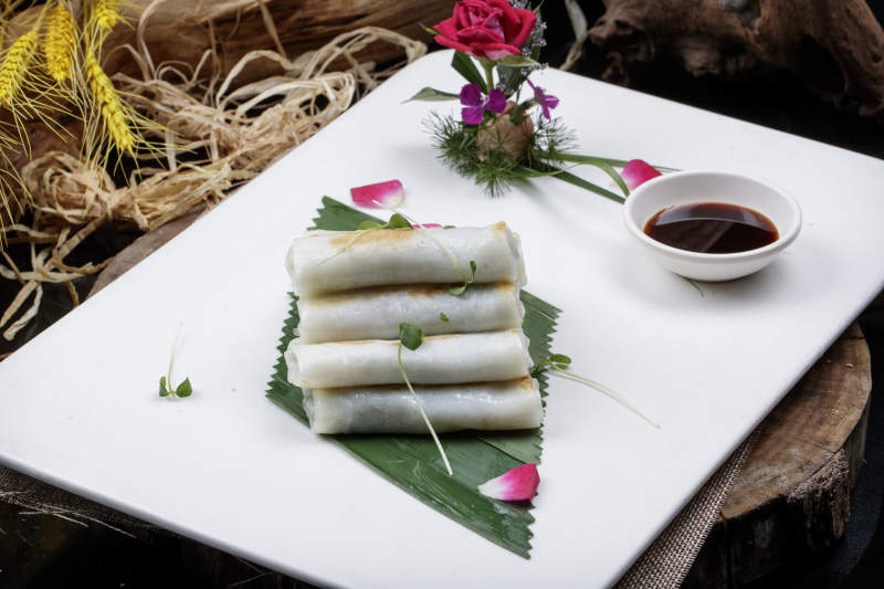 方形瓷盘装的河内肠粉摆放在黑色背景上图片