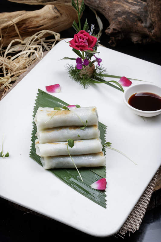 方形瓷盘装的河内肠粉摆放在黑色背景上图片