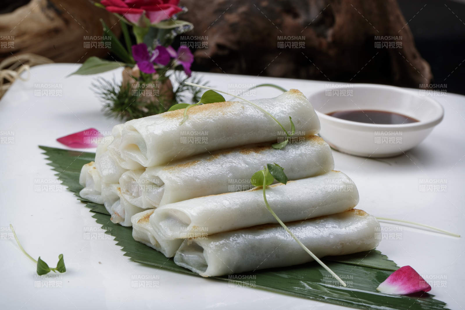 方形瓷盘装的河内肠粉摆放在黑色背景上图片