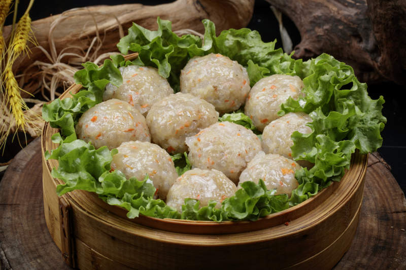 笼屉装的粉蒸土豆大丸子摆放在樟木砧板上图片