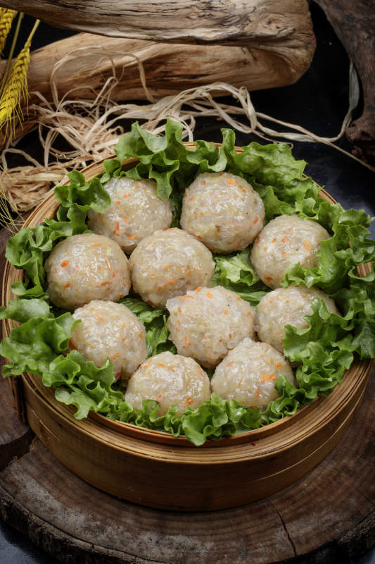 笼屉装的粉蒸土豆大丸子摆放在樟木砧板上图片