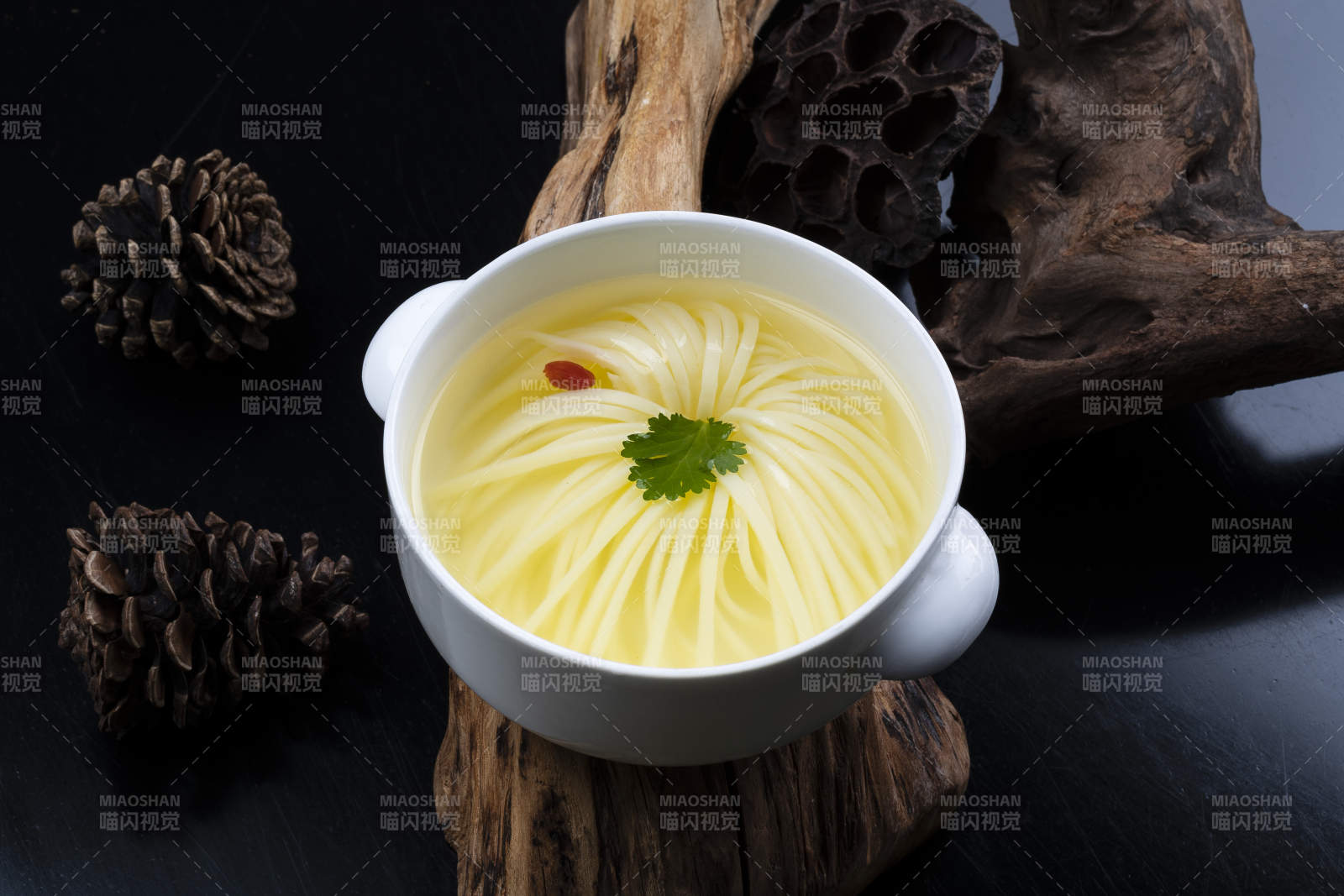 白色汤盅装的文菊豆腐养生汤摆放在崖柏根上图片