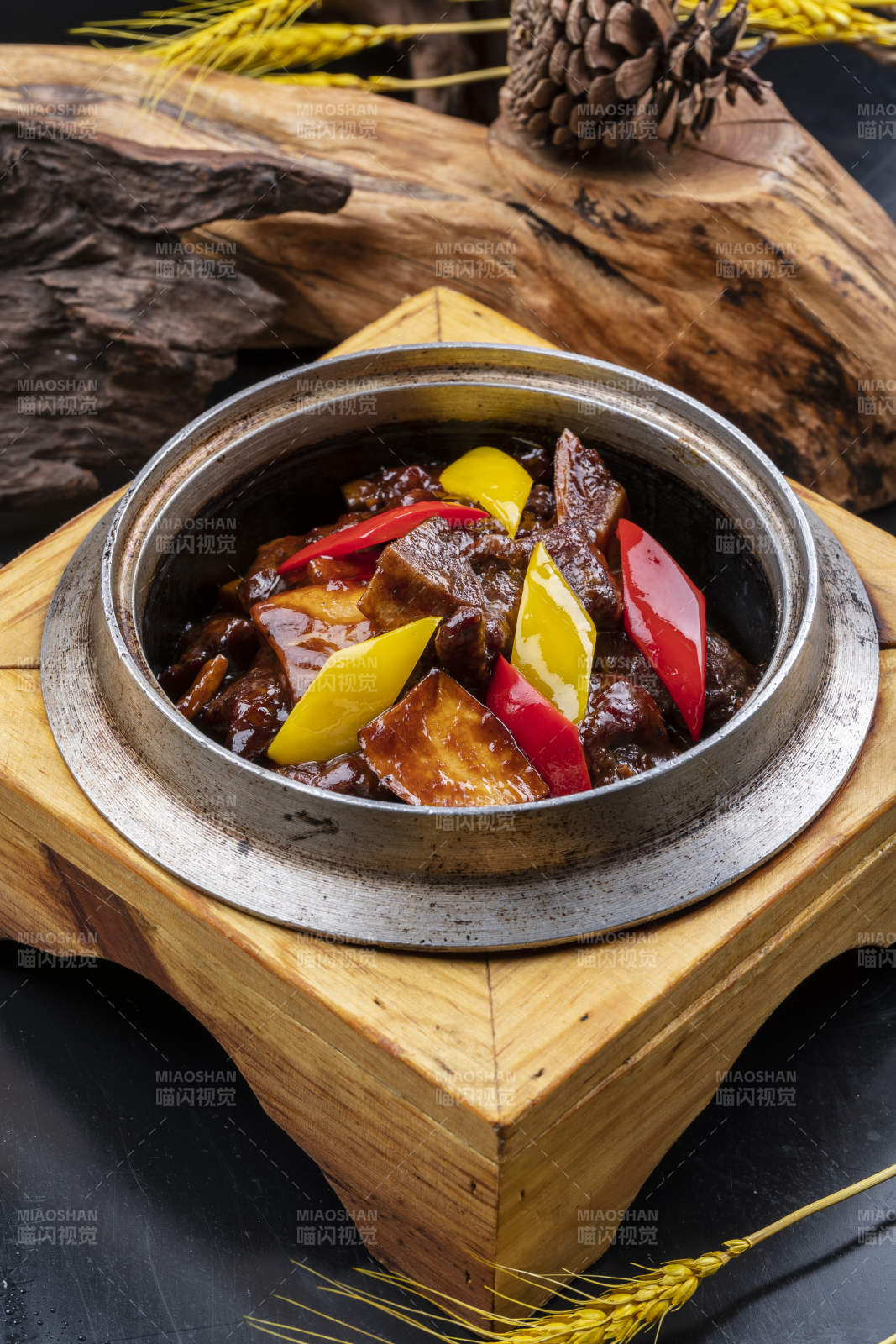 木托铁锅装的酱爆牛仔骨摆放在黑色背景上图片