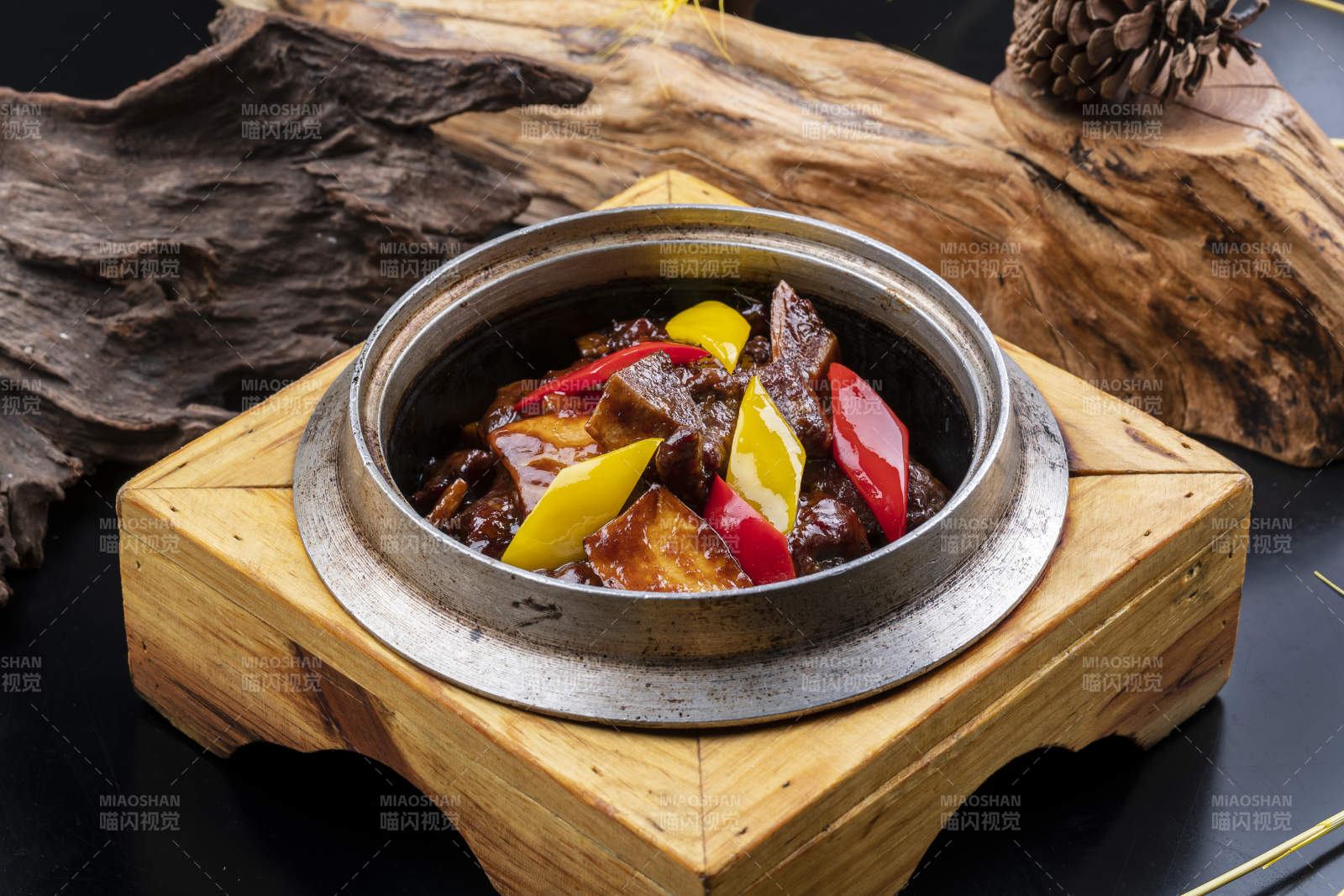 木托铁锅装的酱爆牛仔骨摆放在黑色背景上图片