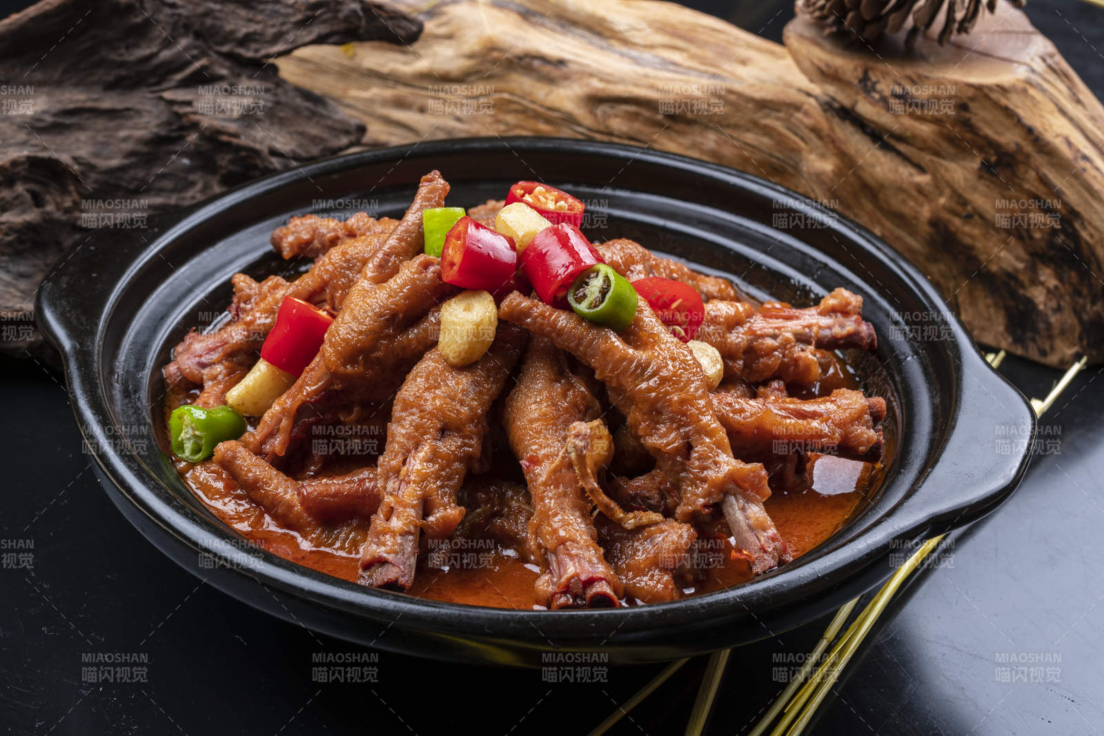蒜香砂锅煲凤爪摆放在黑色背景上图片