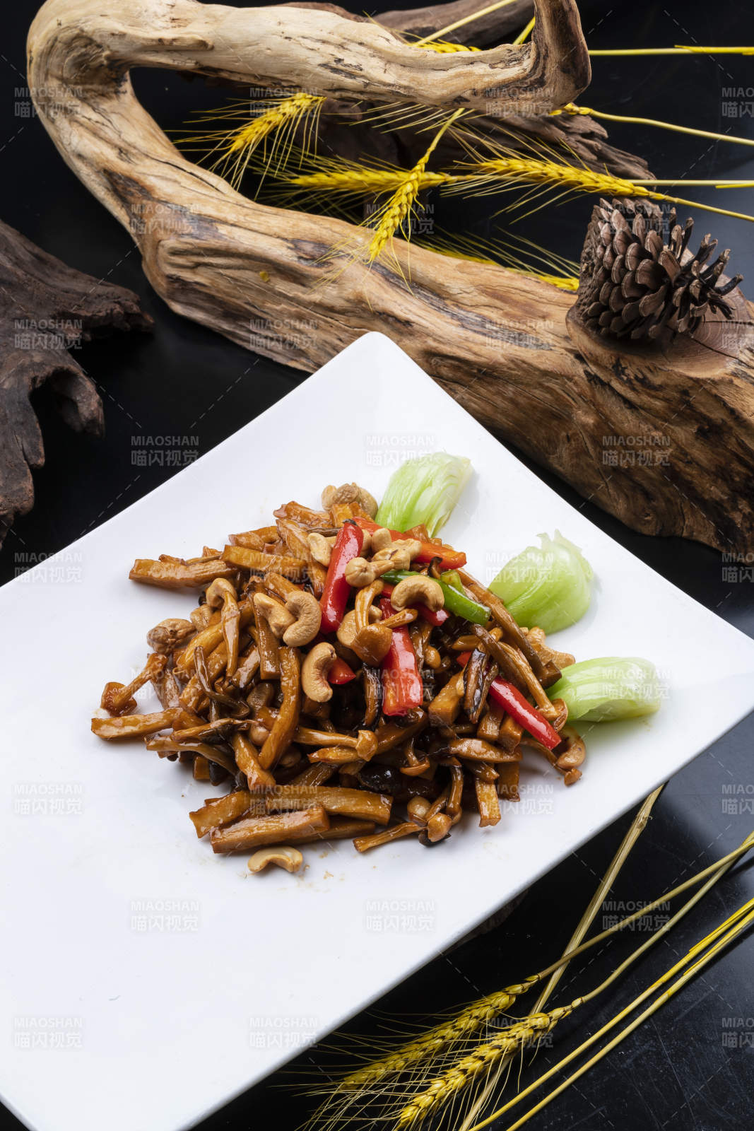 长方形瓷盘装的腰果杭椒杏鲍菇摆放在黑色背景上图片