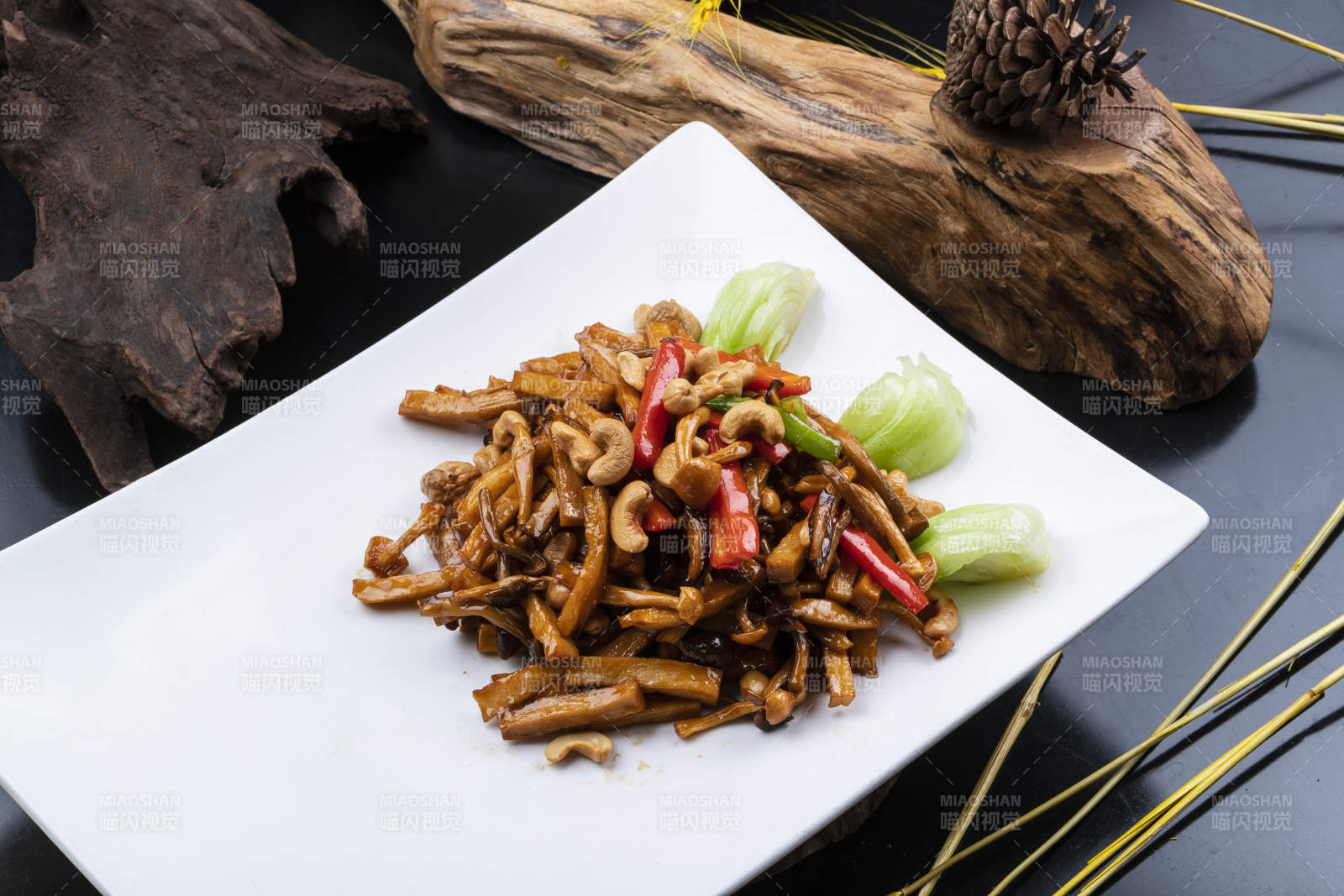 长方形瓷盘装的腰果杭椒杏鲍菇摆放在黑色背景上图片