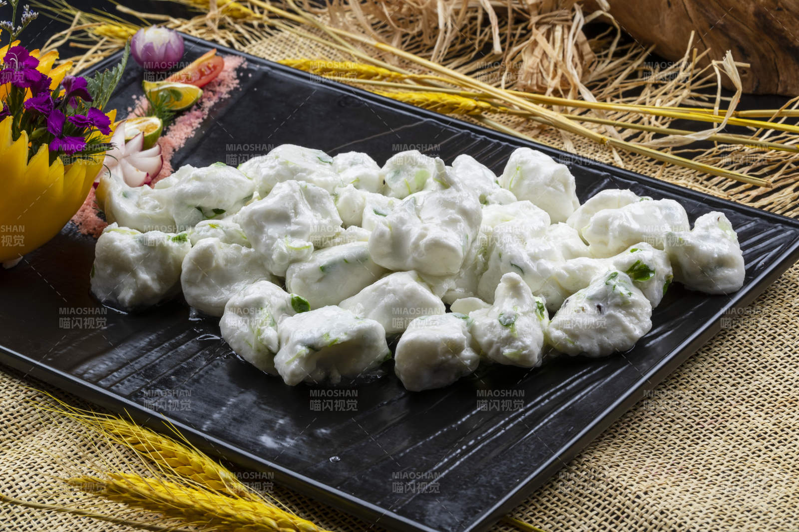 黑色石盘装的香椿芽炒飞龙摆放在麻布垫子上图片