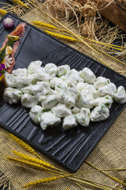 黑色石盘装的香椿芽炒飞龙摆放在麻布垫子上图片