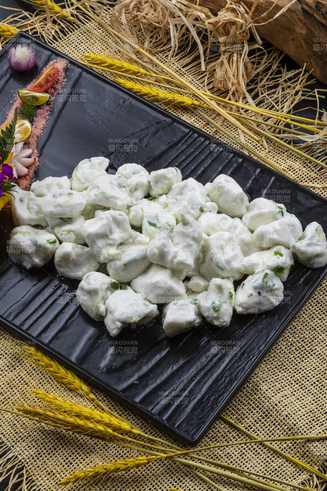 黑色石盘装的香椿芽炒飞龙摆放在麻布垫子上图片