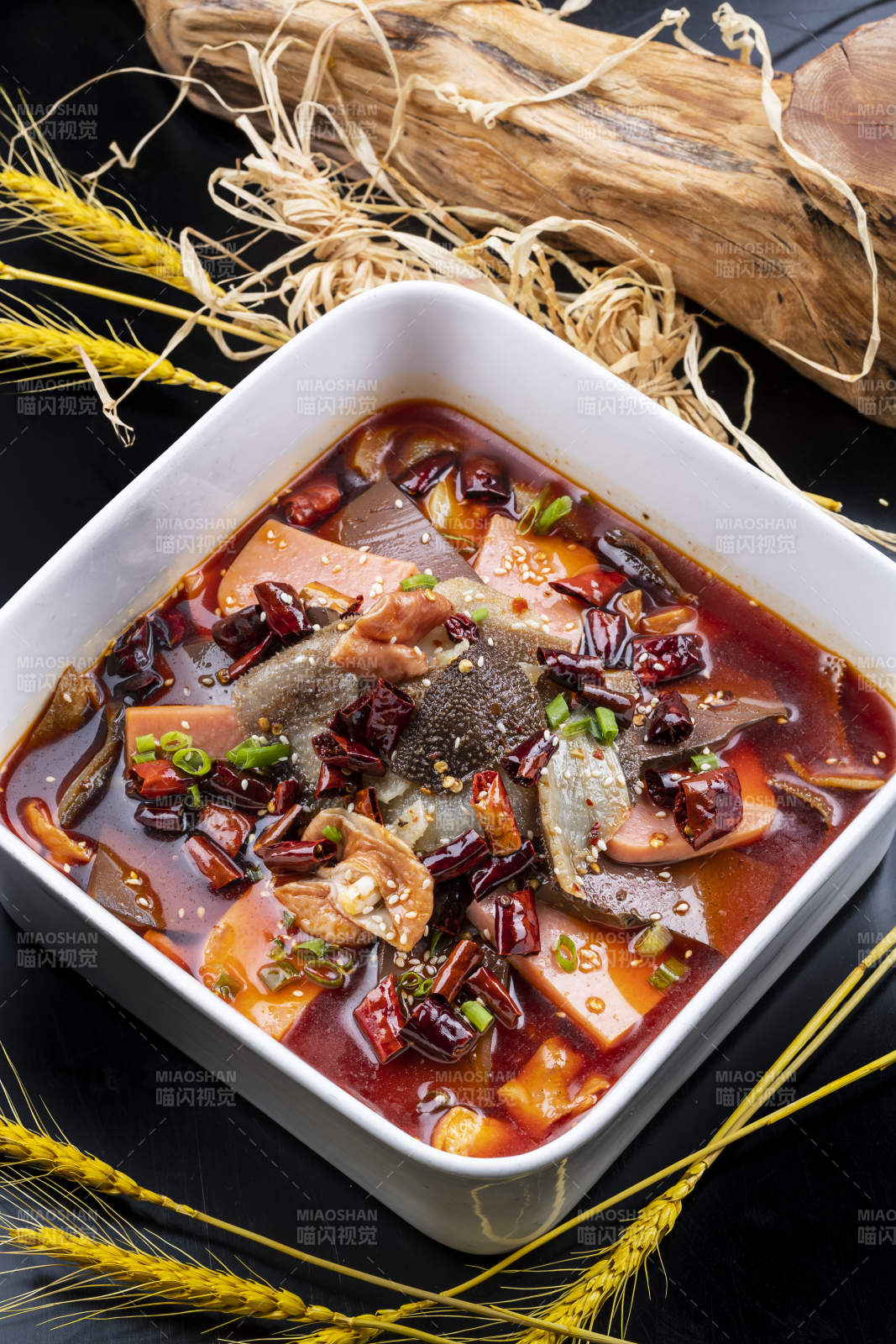 方形汤盆装的川香毛血旺摆放在黑色背景上图片
