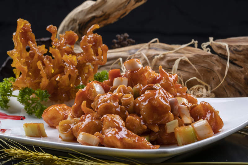 造型奇特的的宫保大虾球摆放在黑色背景上图片