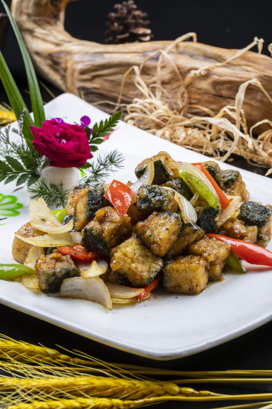 椒麻炸深海鱼块摆放在黑色背景上图片