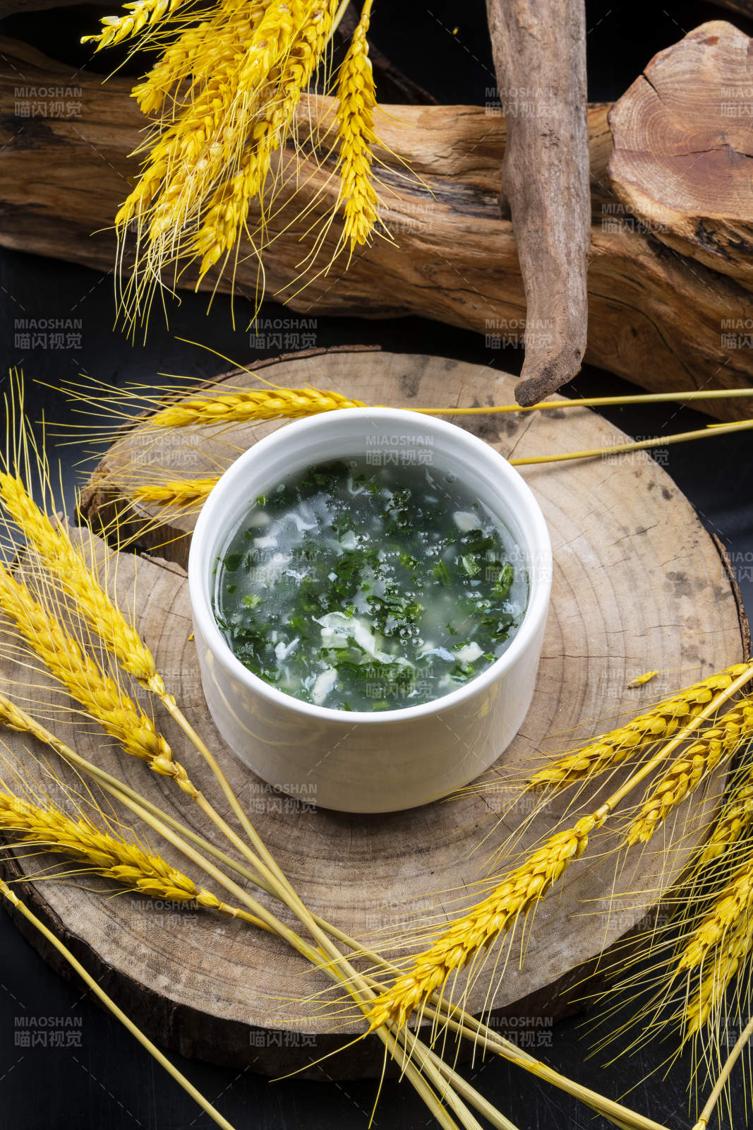 汤盅装的菠菜蛋花羹摆放在樟木砧板上图片