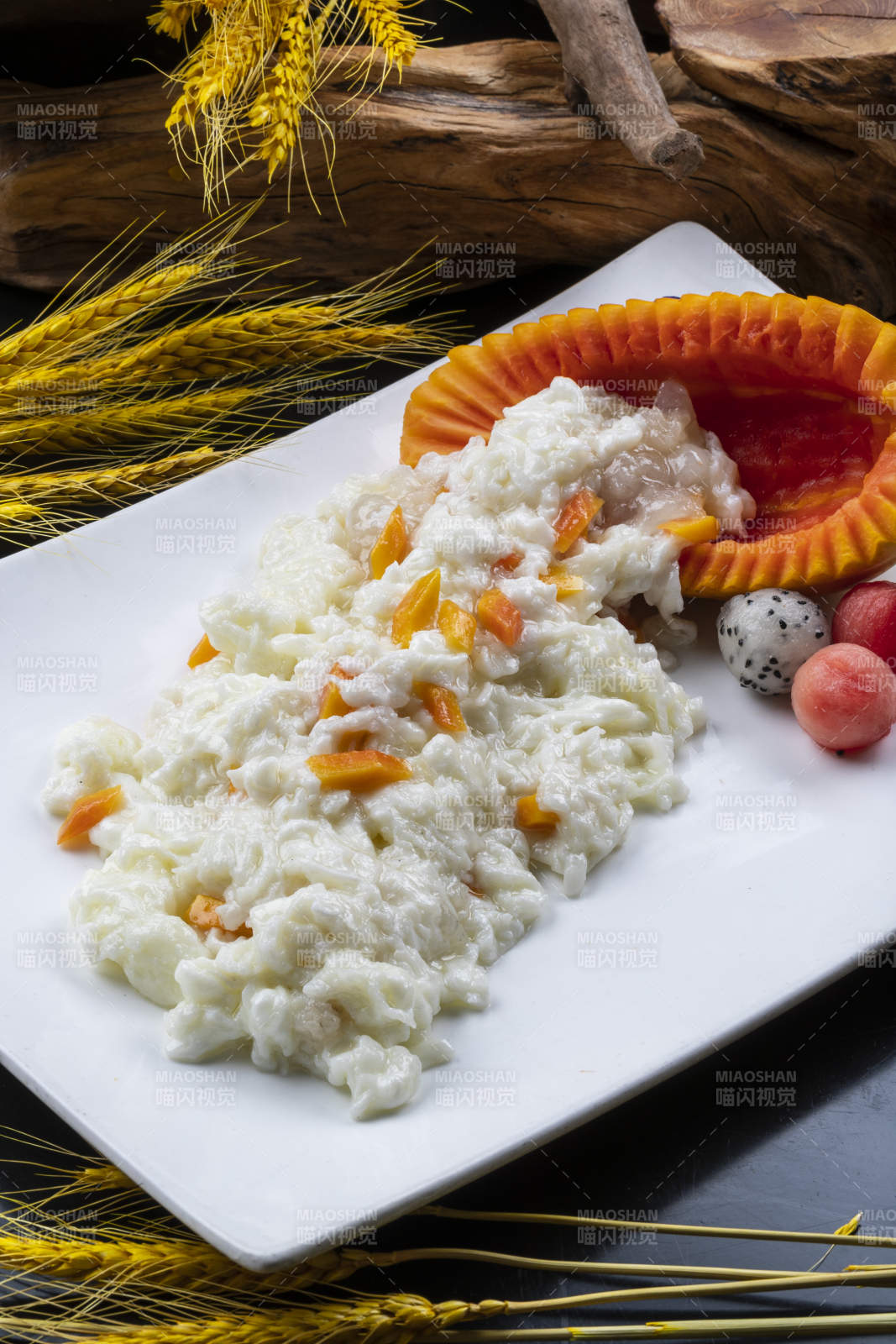 长方形瓷盘装的木瓜芙蓉蛋摆放在黑色背景上图片